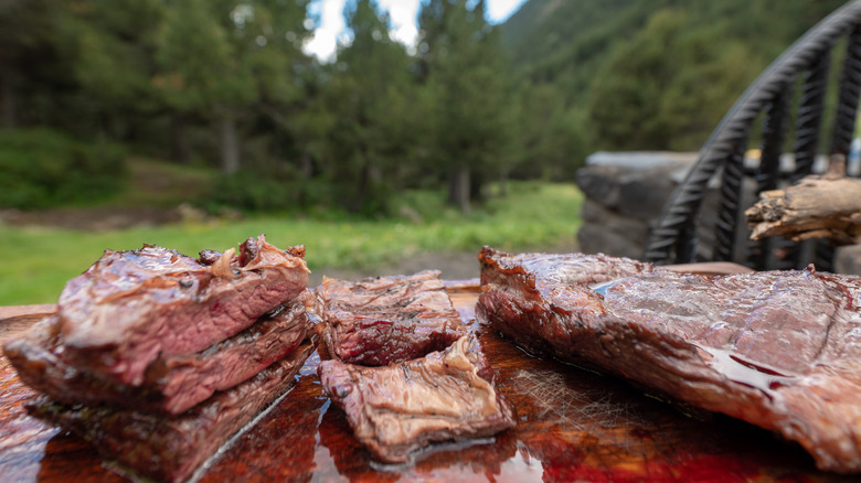 meat cuts cooked outdoors over a wood fire