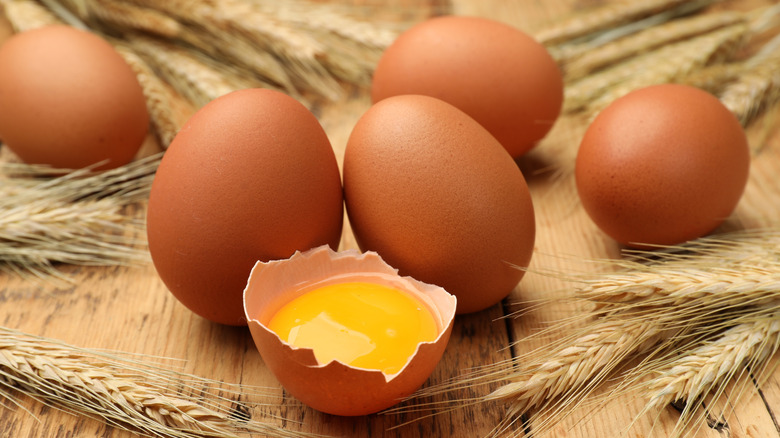 Cracked egg on table with whole eggs