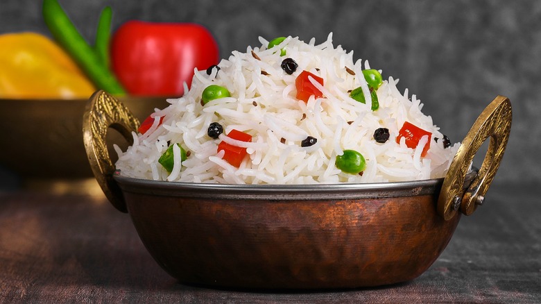 A bowl of fluffy white rice with peas and bell peppers