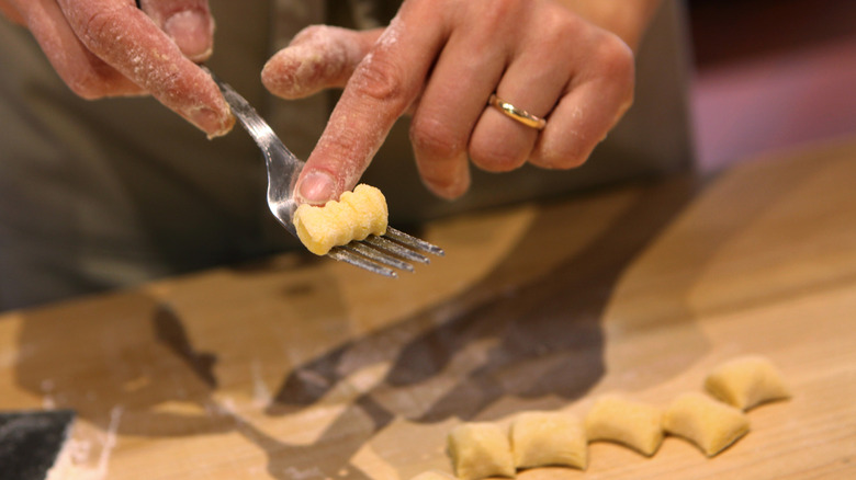 Closeup of a woman's hand making gnocchi from fresh dough