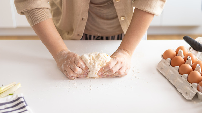Person kneading pasta dough with their hands