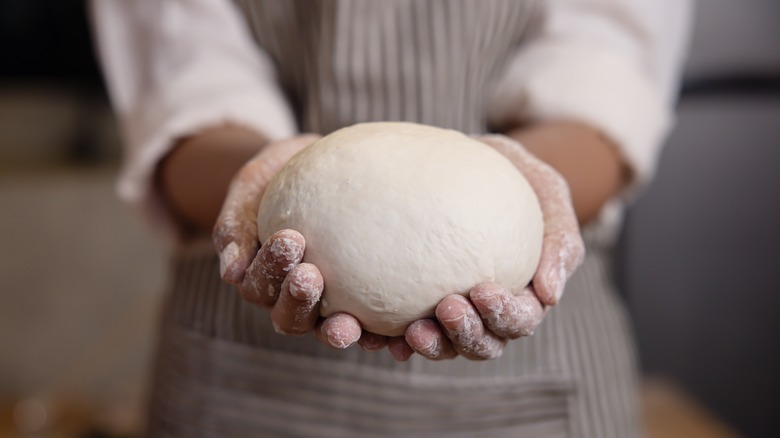 Baker holding bread dough