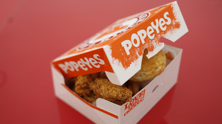 A box of Popeyes chicken with a biscuit