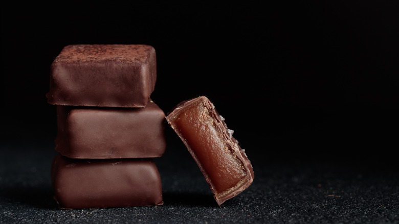 Chocolate handcrafted bonbons and cutted piece of candy with caramel on a black background