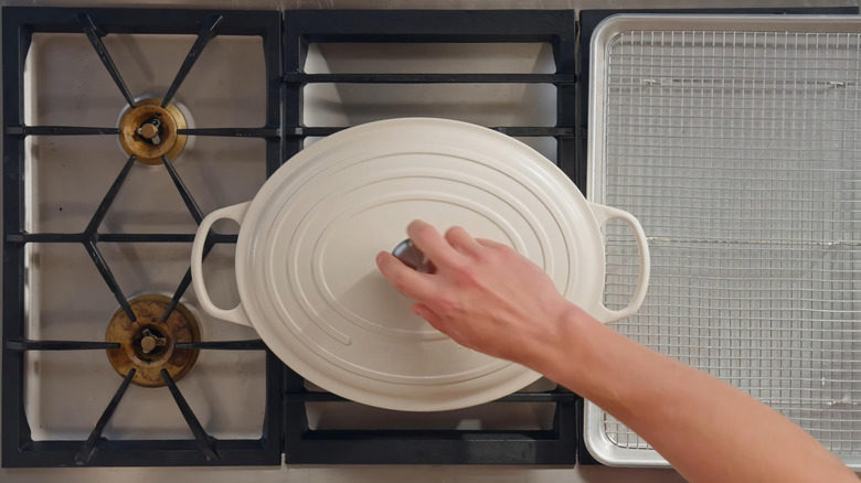 Person with hand on Dutch oven lid