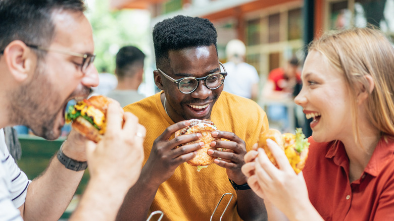 Group of people eating fast food burgers outside