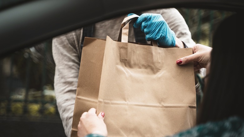 Grocery store worker delivering items to customer in car