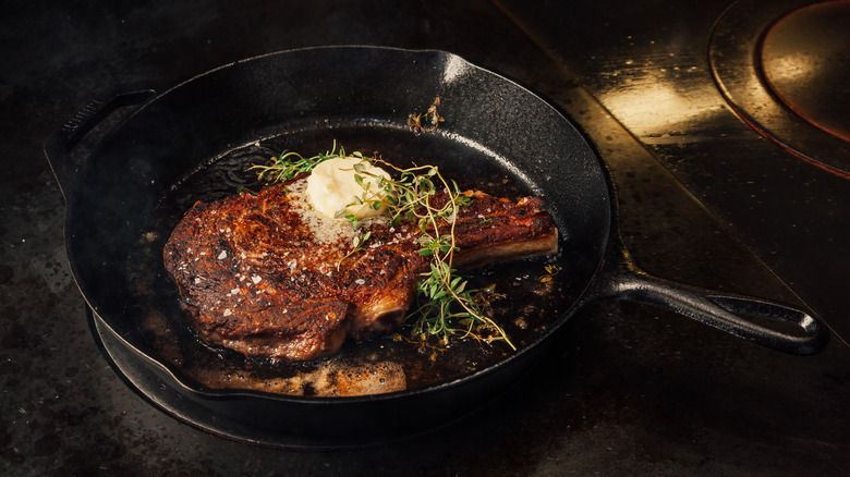 tomahawk steak cooking in a cast-iron pan
