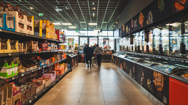 An Aldi shopping aisle with shelves on one side and coolers on the other