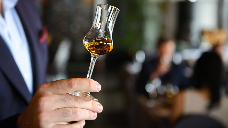 Person swirling whiskey in small tulip glass