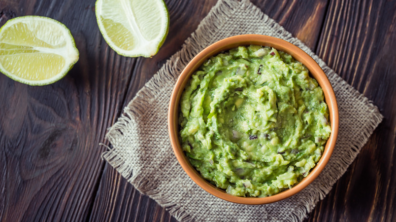 Guacamole in a bowl with limes