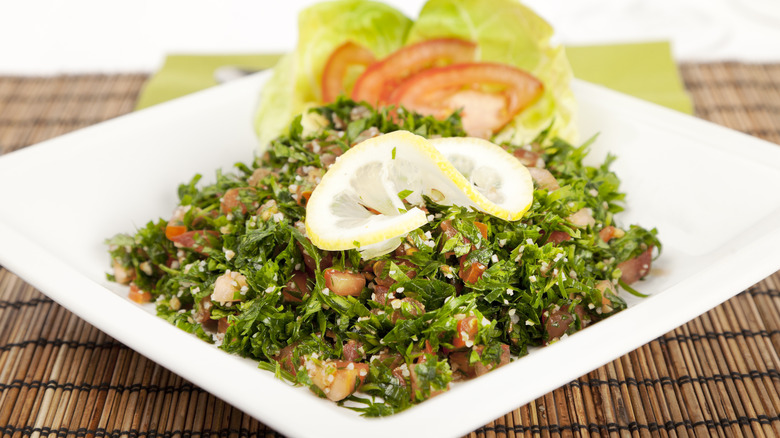 Tabbouleh salad garnished with lemon and tomato