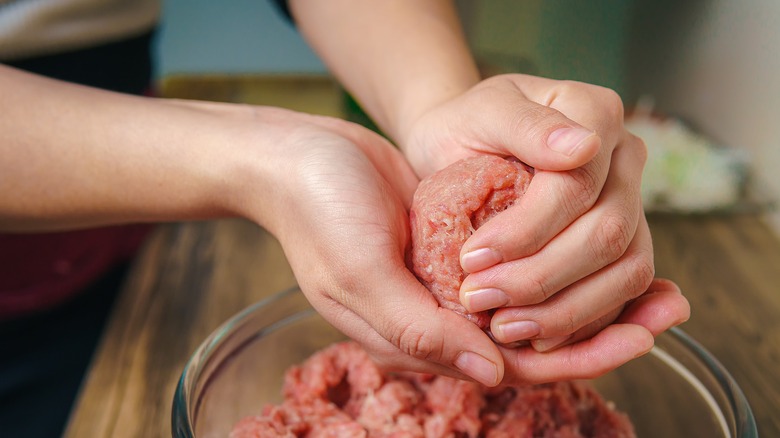 Woman's hands forming ground meat