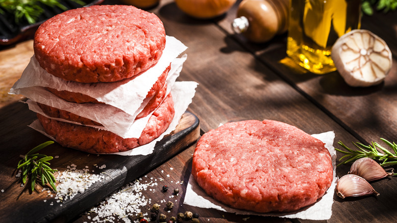 Raw burger patties on table