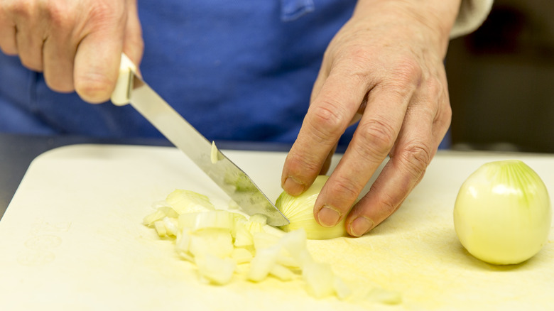 hands cutting onions on a cutting board