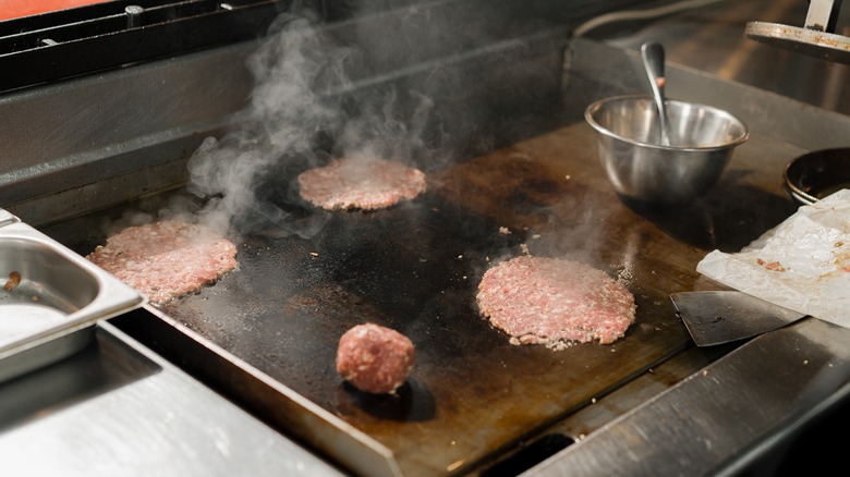 smash burgers cooking on griddle
