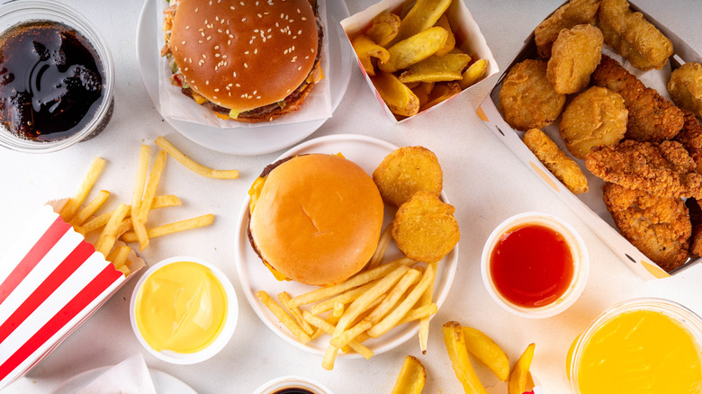 Fast food burgers, sandwiches, fries, and chicken on table
