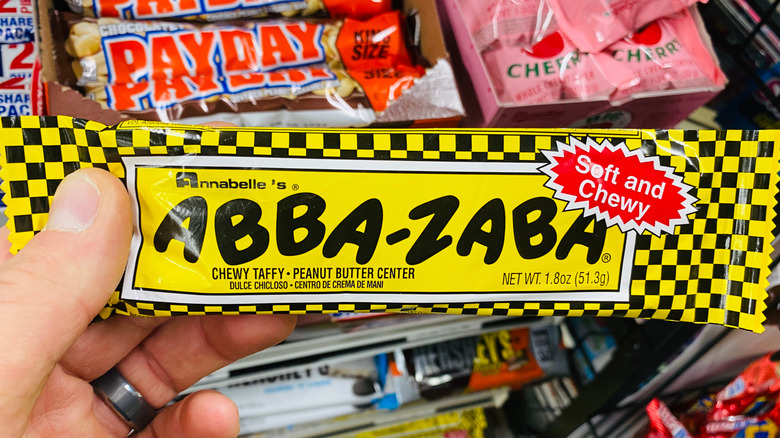 Hand holds up an abba-zaba candy bar in front of other candies
