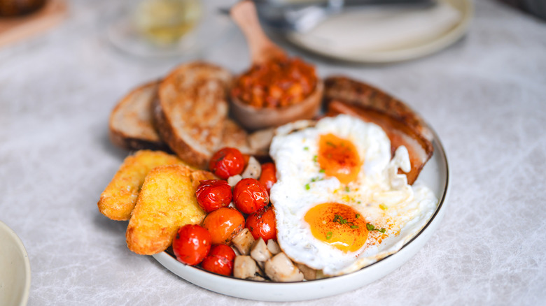 English breakfast on a plate with eggs, tomatoes and sausage