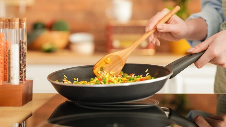 Person stirring rice and veggies in pan