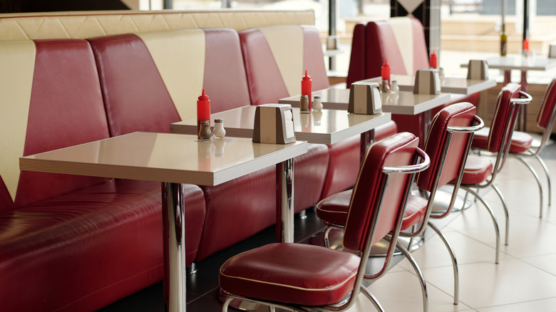 Interior of a retro-style diner, showing booth seating and old-fashioned ketchup bottles