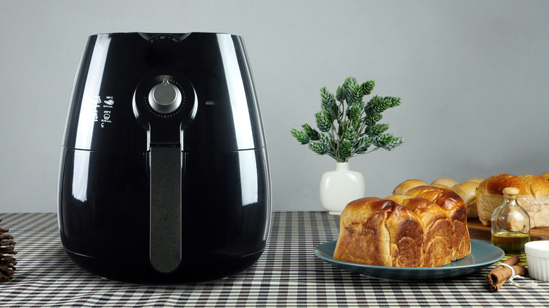 black air fryer next to bread on table