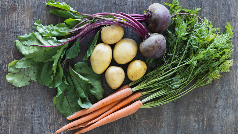 Raw potatoes, beets, and carrots on table