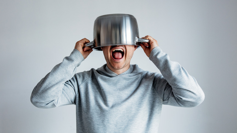 Man yelling with silver pot over head