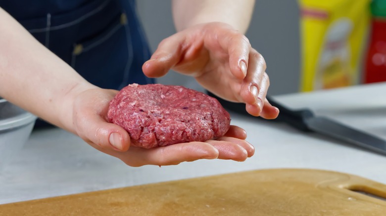 shaping beef patty over board