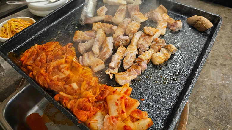A grill with pork belly and kimchi