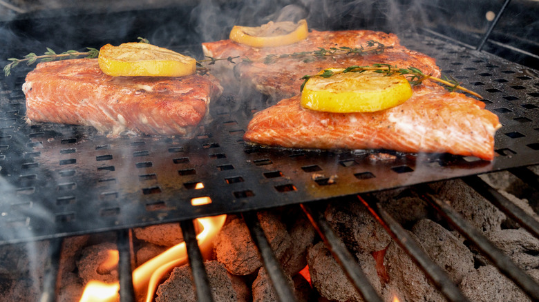 salmon topped with lemon and herbs on the grill