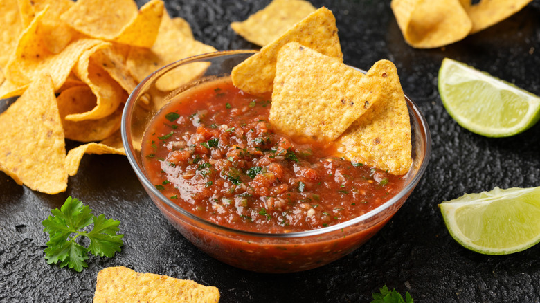 Tortilla chips in a small bowl of tomato salsa