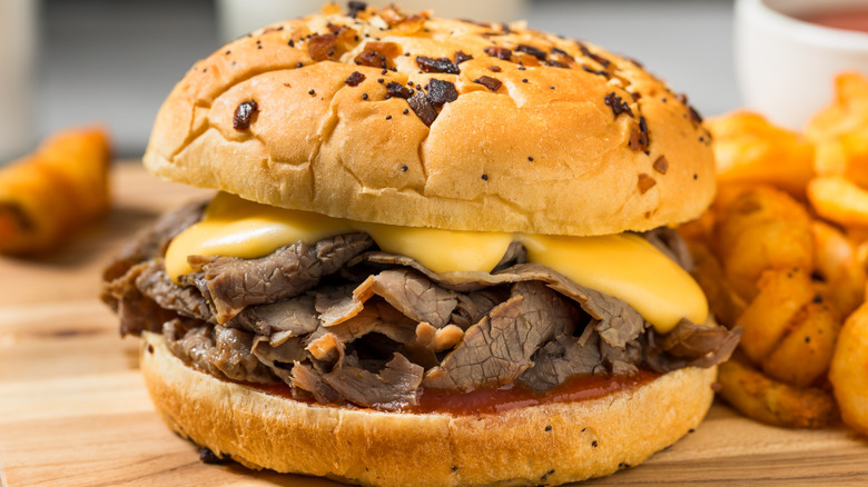 A roast beef sandwich with cheddar cheese sauce and curly fries