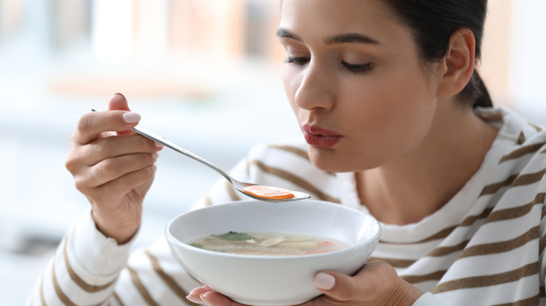 Woman blowing on soup 