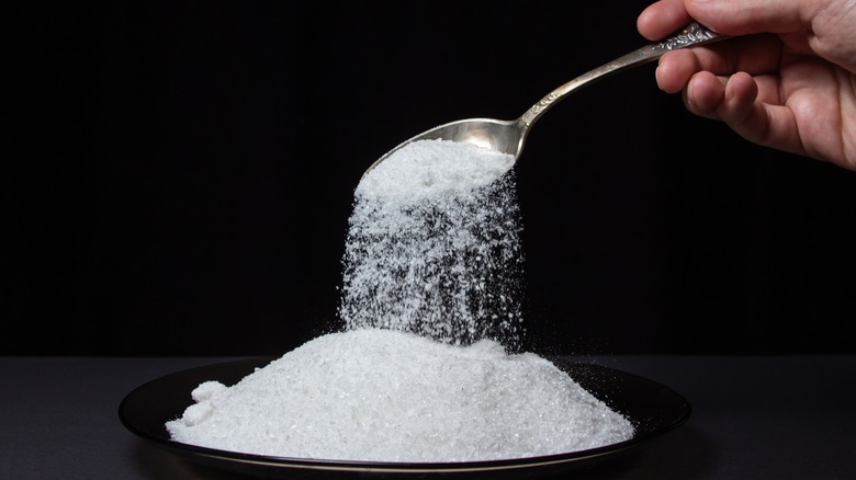 Person pouring spoonful of salt onto pile of salt