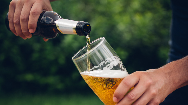 Person pouring beer from bottle to glass