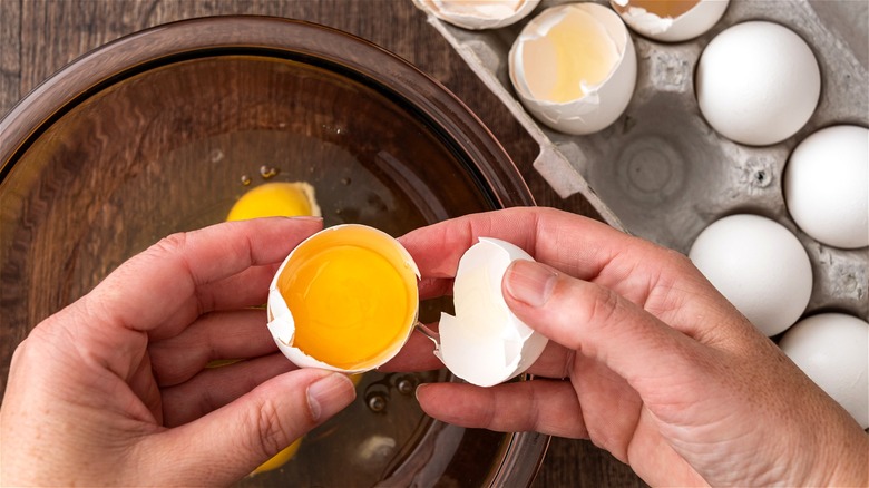 Hands cracking egg over bowl