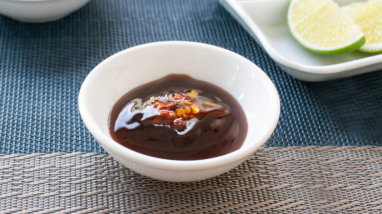 Bowl of homemade hoisin sauce in a white dish on a wicker table..