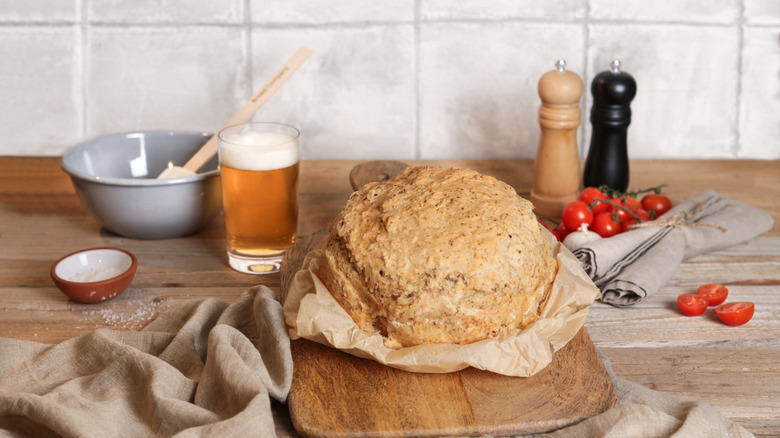 Loaf of rustic bread on a kitchen counter with a glass of beer