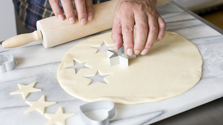 person making sugar cookies with rolling pin and stamps
