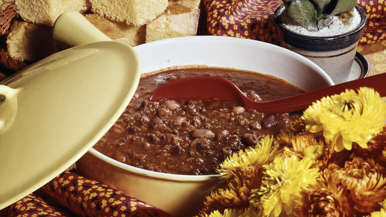 a pot of chili surrounded by flowers and harvest foods