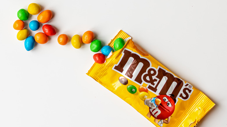 Colorful chocolates spilling from an M&M pouch