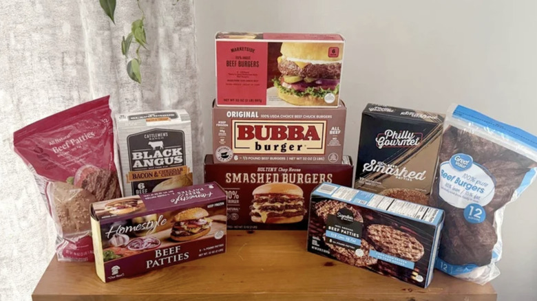 Packages of frozen burgers on wooden table