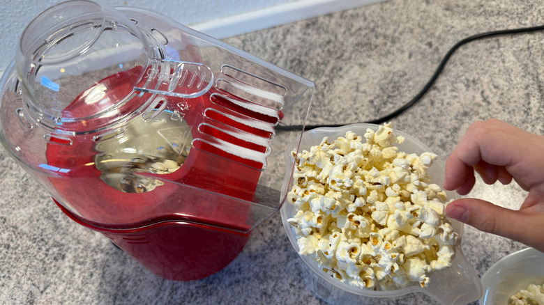 Overhead view of a red air popper with a cup of popcorn next to it