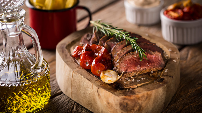 sliced picanha with roasted vegetables on a piece of wood