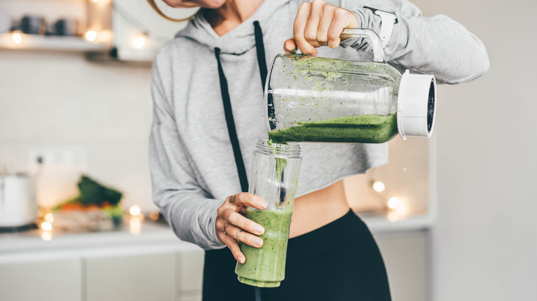 pouring green smoothie into glass