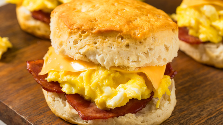 Close-up of a bacon, egg, and cheese biscuit on a cutting board