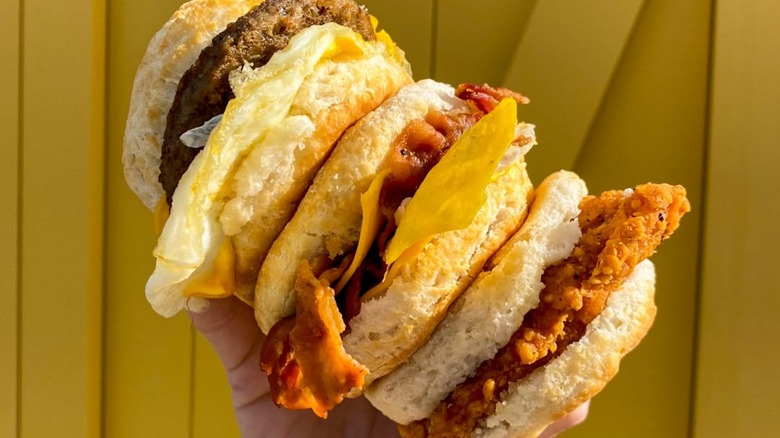 Hand holding three Biscuitville breakfast sandwiches