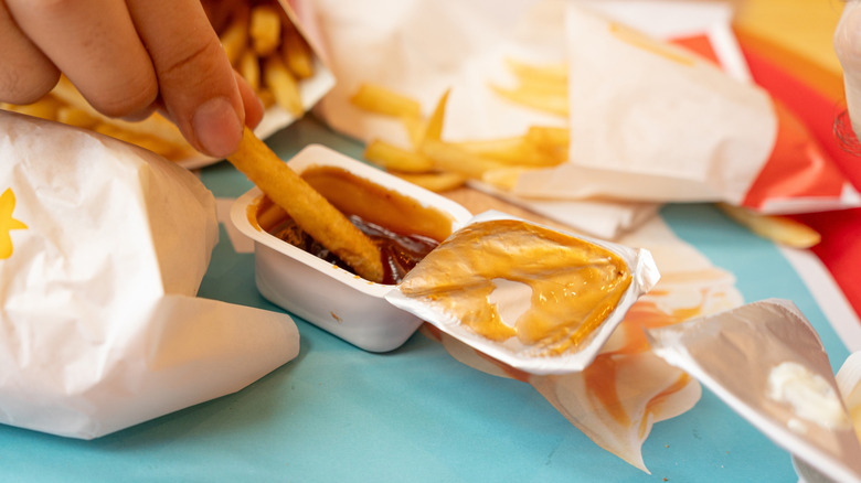 Man dunking a fry in a McDonald's dip with a foil top