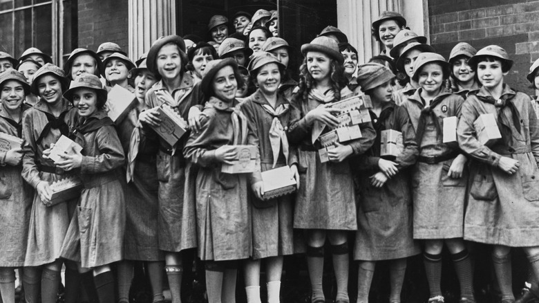 Black and white photo of Girl Scouts holding boxes of cookies